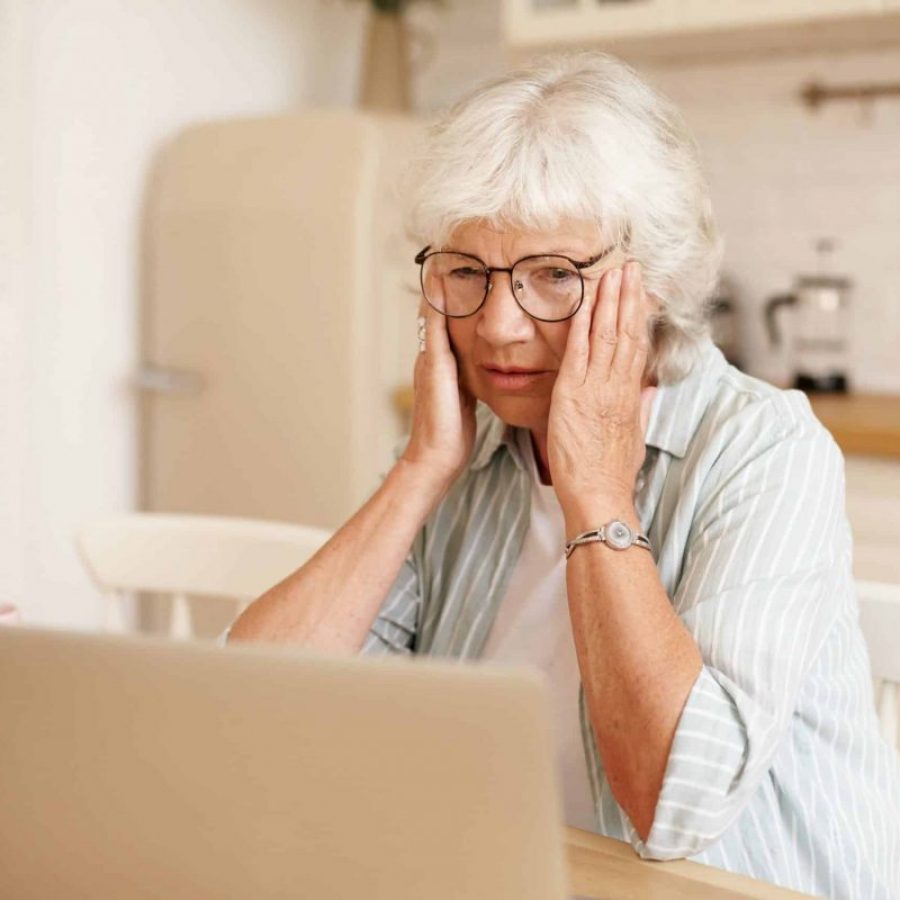 Une dame senior devant son ordinateur agacée car celui-ci est lent